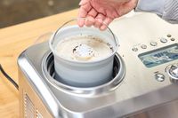 A hand removing a pint of ice cream from the Breville Smart Scoop Ice Cream Compressor