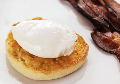 Perfectly poached egg resting on a toasted, buttered English muffin halve
