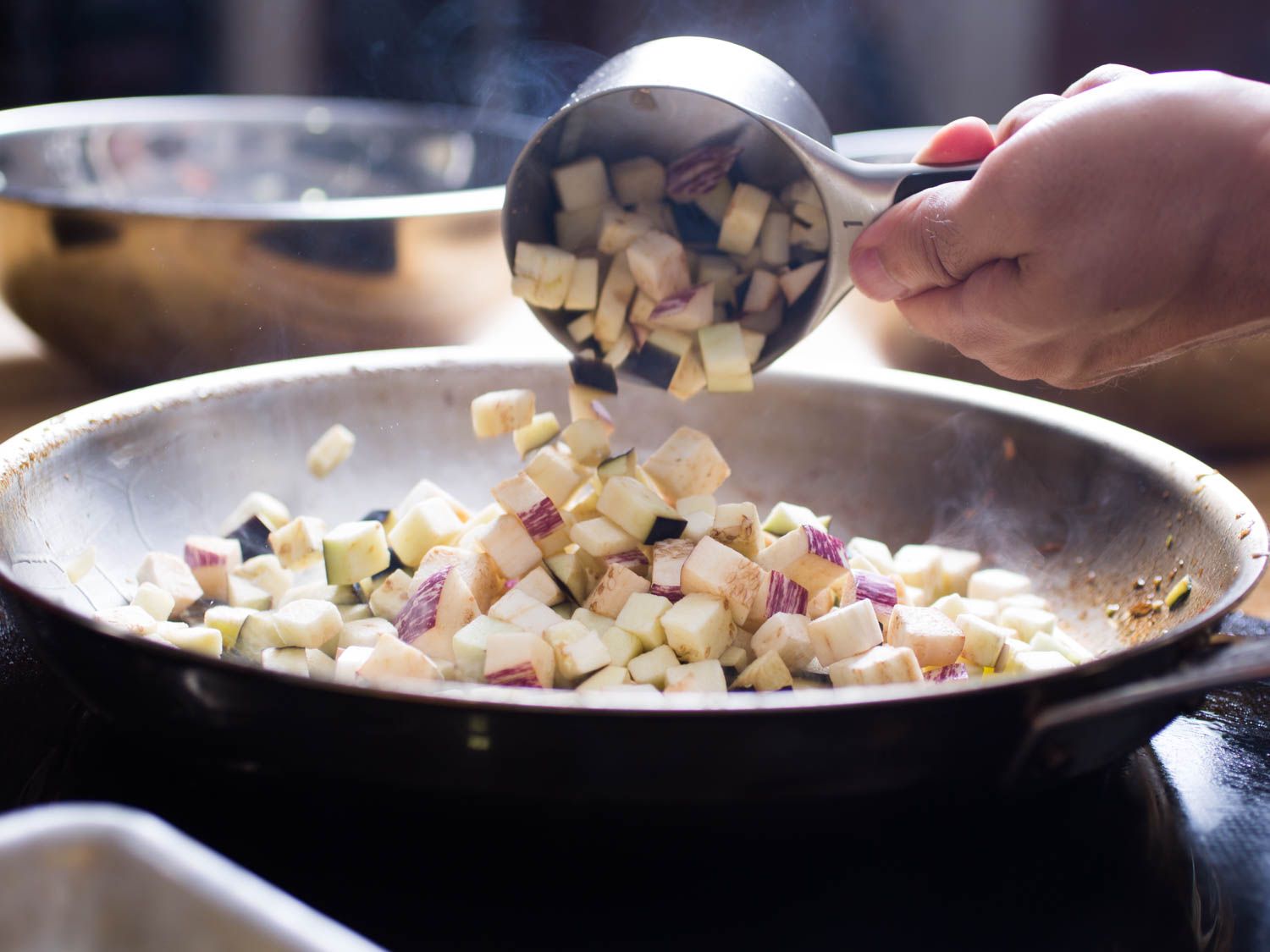 Diced eggplant is added to the skillet.
