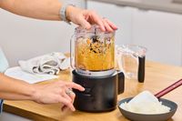 A person finely chops veggies in the KitchenAid Go Cordless 5-Cup Food Chopper