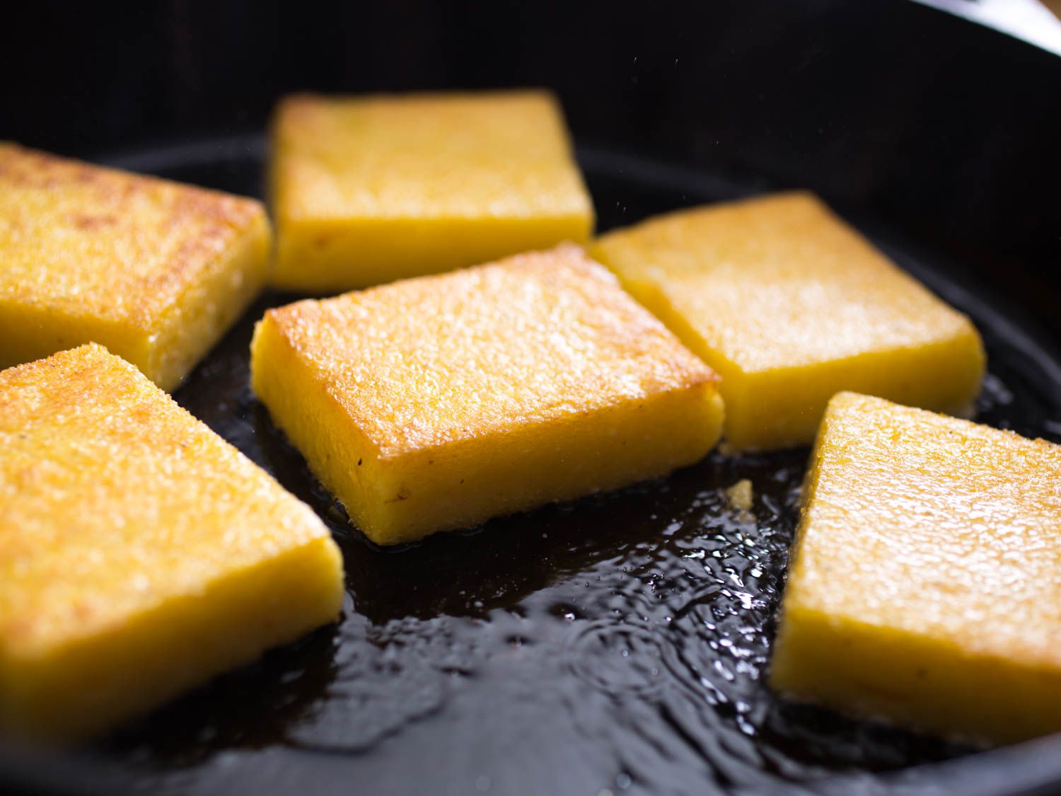 Cooking crisp polenta squares in a cast iron skillet.