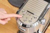 A person presses a button on the De'Longhi EC900M Dedica Maestro Espresso Machine