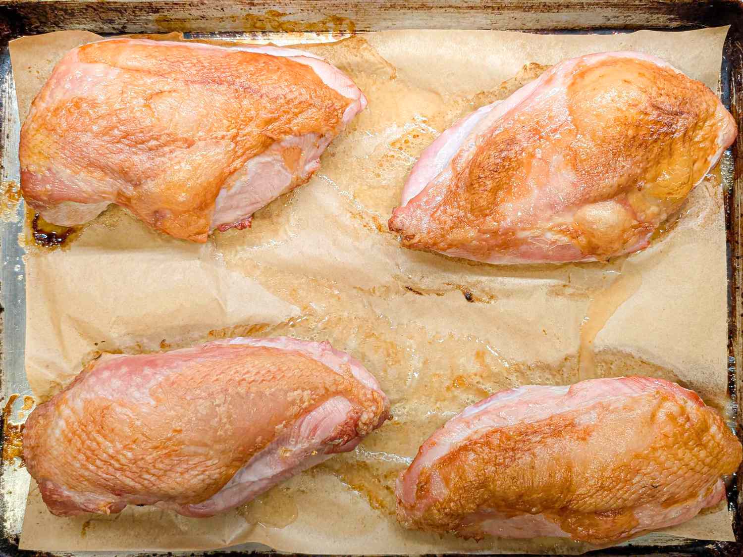 Four roasted turkey breasts on parchmentlined baking tray
