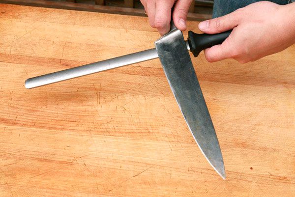 Author uses a diamond steel and a floating grip to hone a chef's knife, starting at the heel.