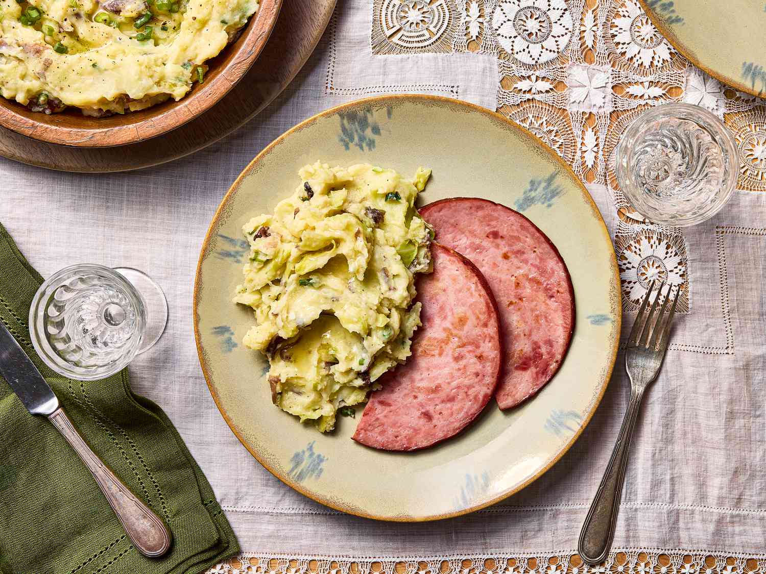 colcannon served with sliced ham on white lace tablecloth 