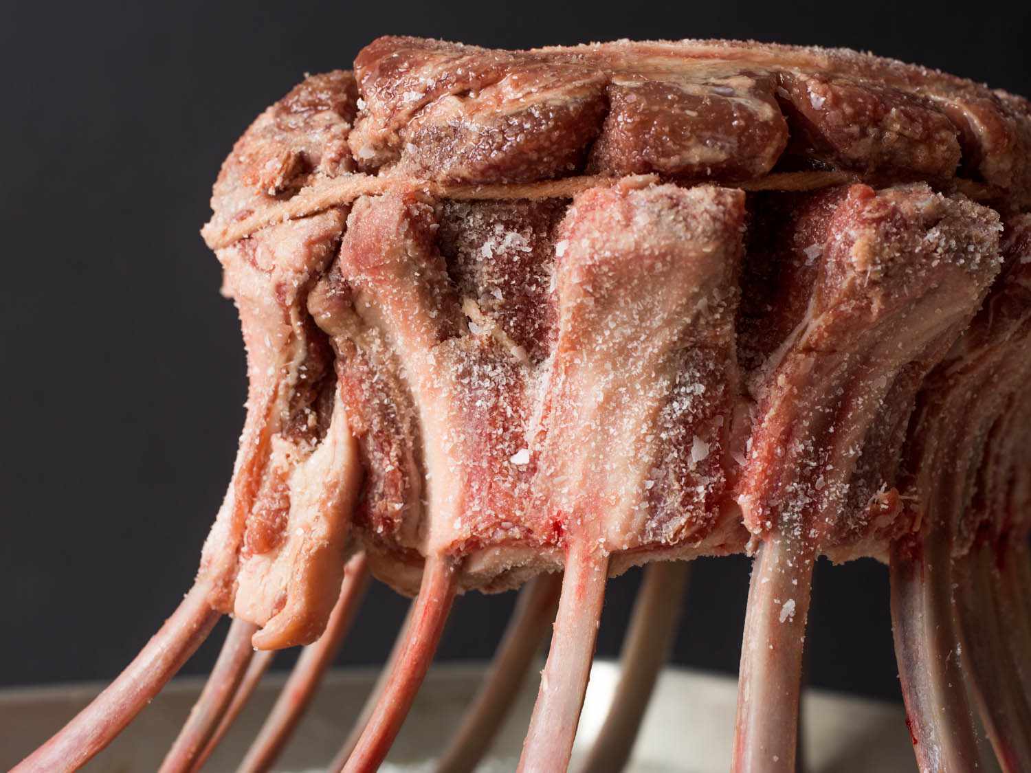 Close-up of lamb ribs that have been bent into a round shape and tied with twine to form a crown roast of lamb.
