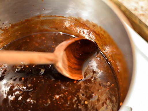 The barbecue sauce is stirred as it simmers.