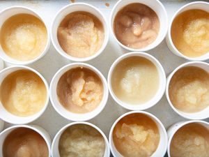 Assorted cups of applesauce displayed in rows on a surface