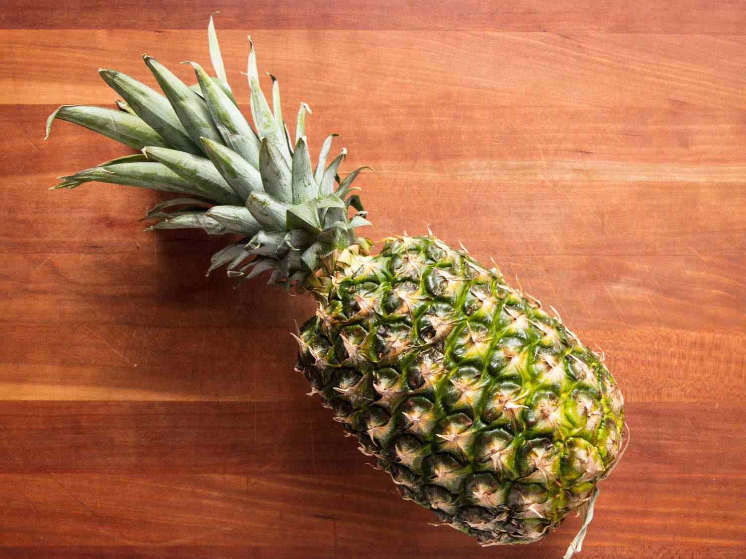 Whole pineapple on cutting board.