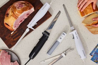 a variety of electric knives on a melamine countertop with ham and a piece of bread
