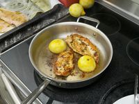 a saute pan with chicken and lemons inside