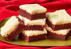 red velvet brownie squares stacked together on a gold platter on top of a red velvet backdrop