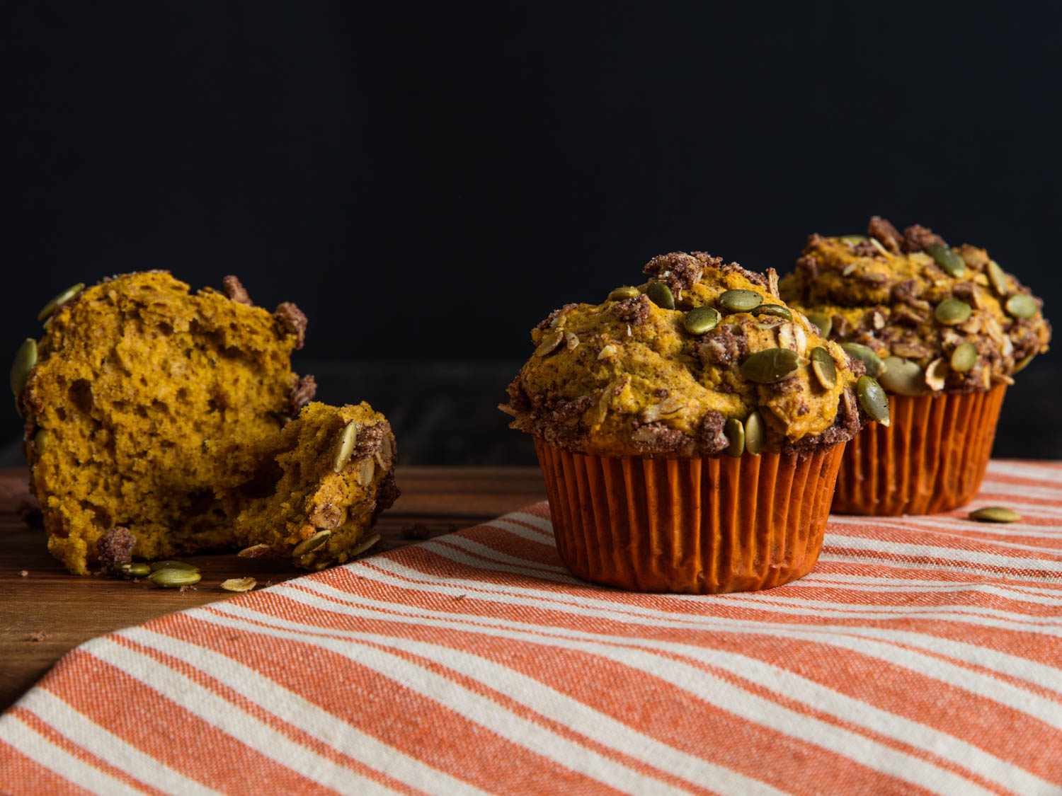 A profile shot of the pumkin streusel muffins. One has been torn apart to reveal the moist interior.