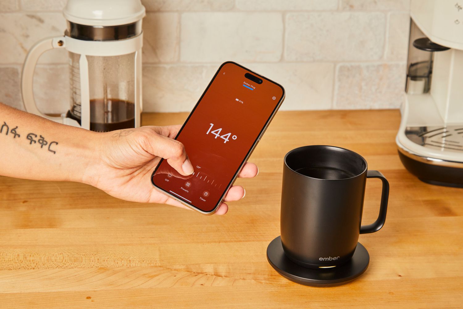 A person uses the Ember Mug app to control the temperature of a cup of coffee.