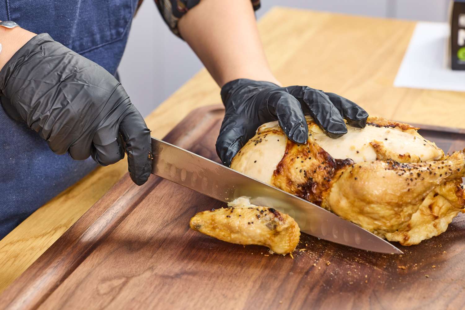 A person cuts meat with the Wüsthof Classic 9 Inch Hollow Edge Carving Knife