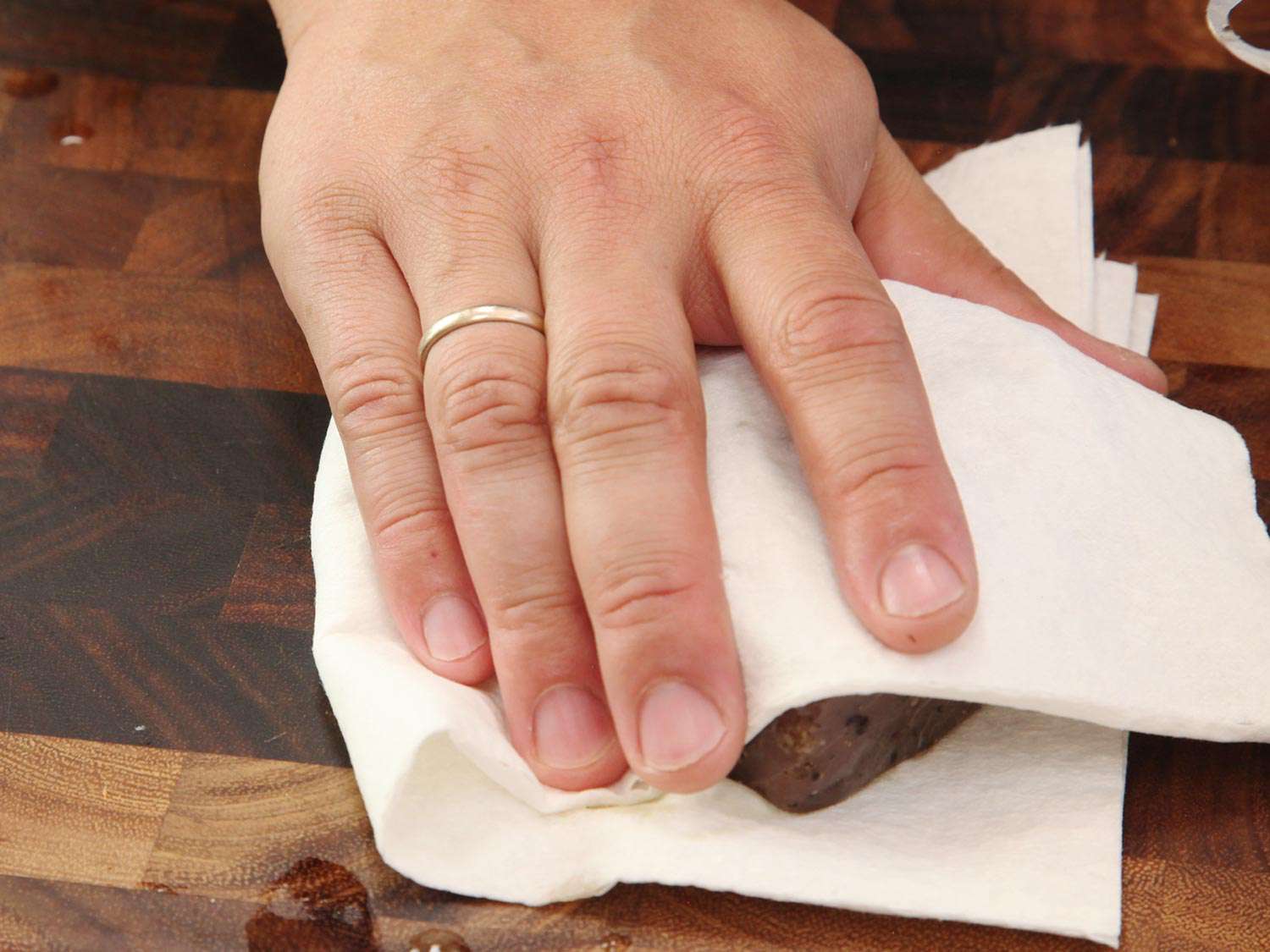 Author drying a cooked tuna steak with a double layer of paper towels.