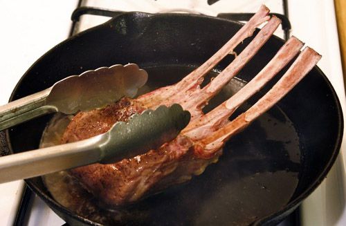 Searing lamb rack in a skillet.