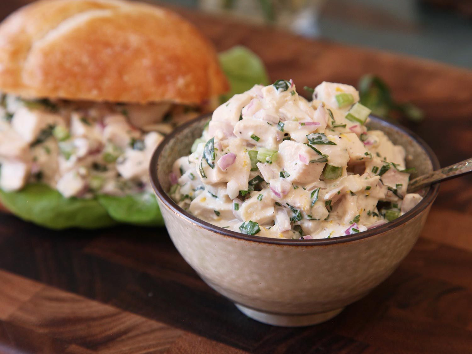 A bowl of chicken salad made with sous vide chicken breast, with a chicken salad sandwich in the background.