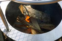 A close-up view of a fire pit with burning wood logs inside