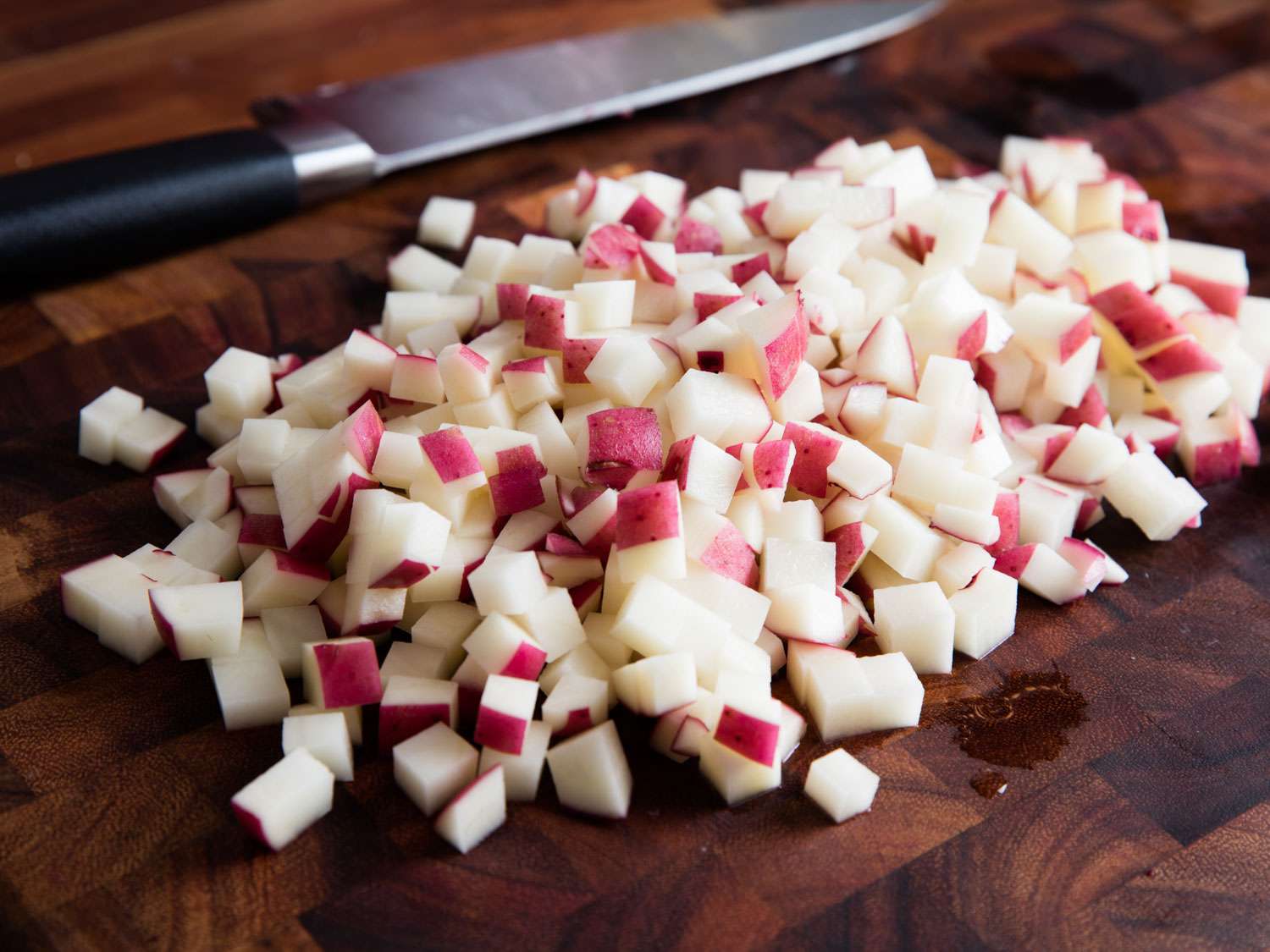 Diced red potatoes on wooden cutting board.