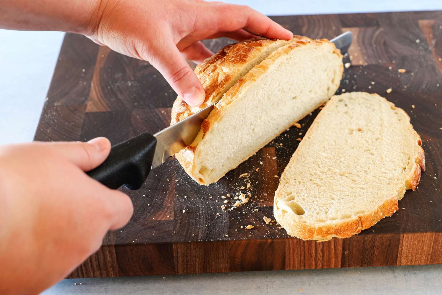 Person slicing bread with Dexter-Russell Basics 10-Inch Bread Knife With Black Polypropylene Handle