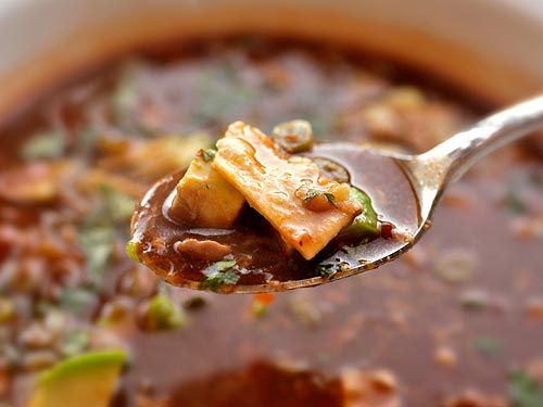 A spoonful of turkey tortilla soup is held up to the camera.
