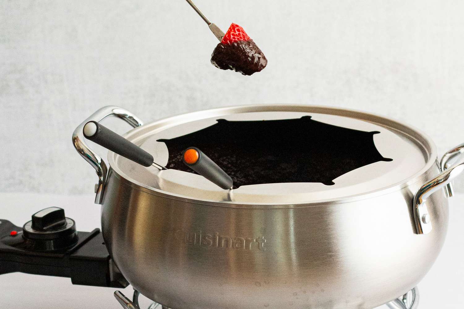 a person removing a strawberry dipped in chocolate