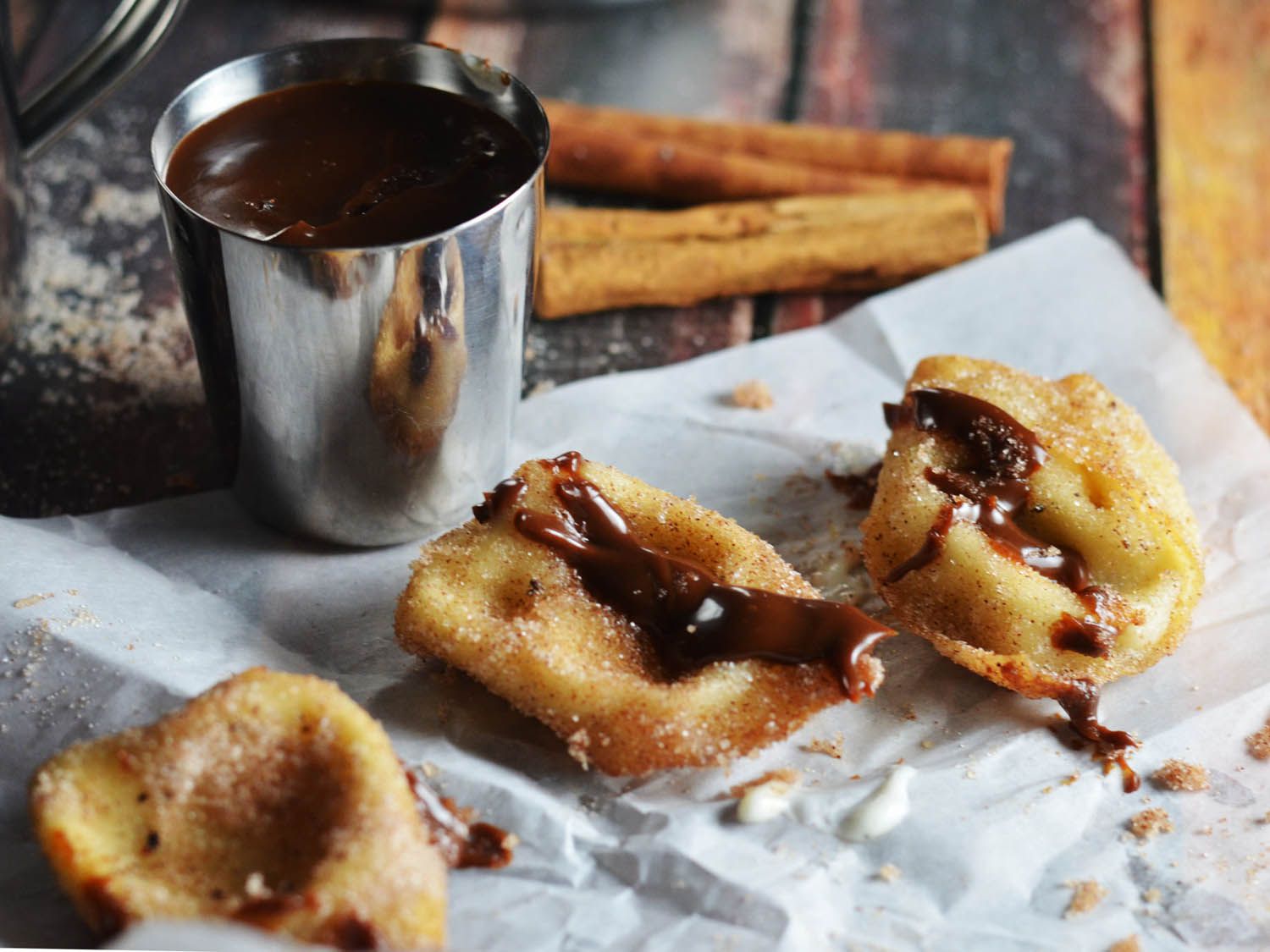 Several cream cheese wontons sit atop a piece of wax paper, drizzled with Nutella sauce.