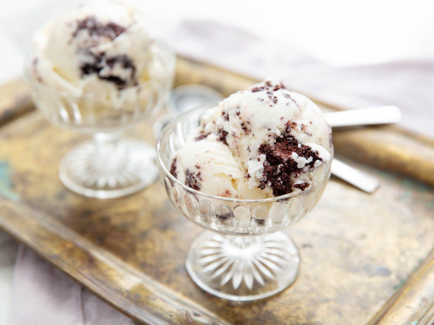 Two scoops of cake scrap ice cream in a frosted glass dish.