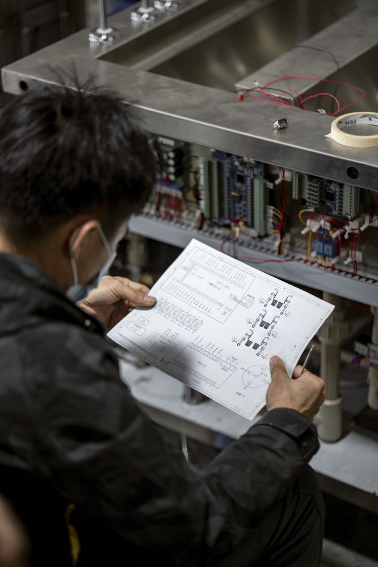 A factory worker looks a printed schema infront of a machine