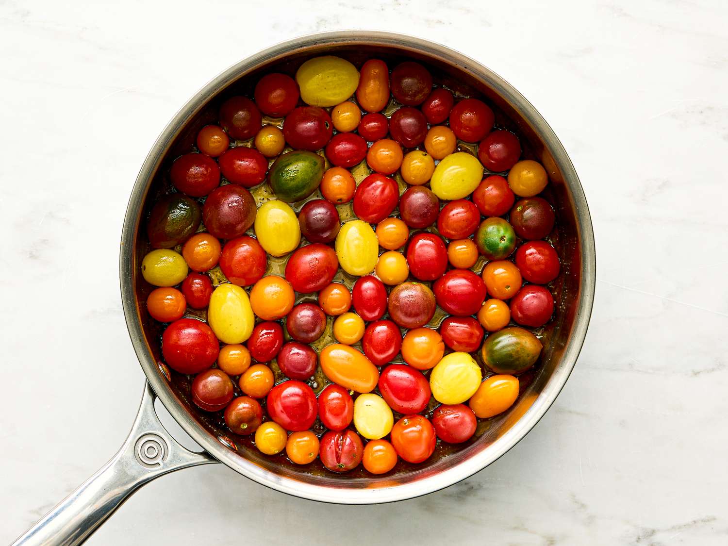 Colorful cherry tomatoes in a saucepan arranged for a tomato tarte tatin preparation step