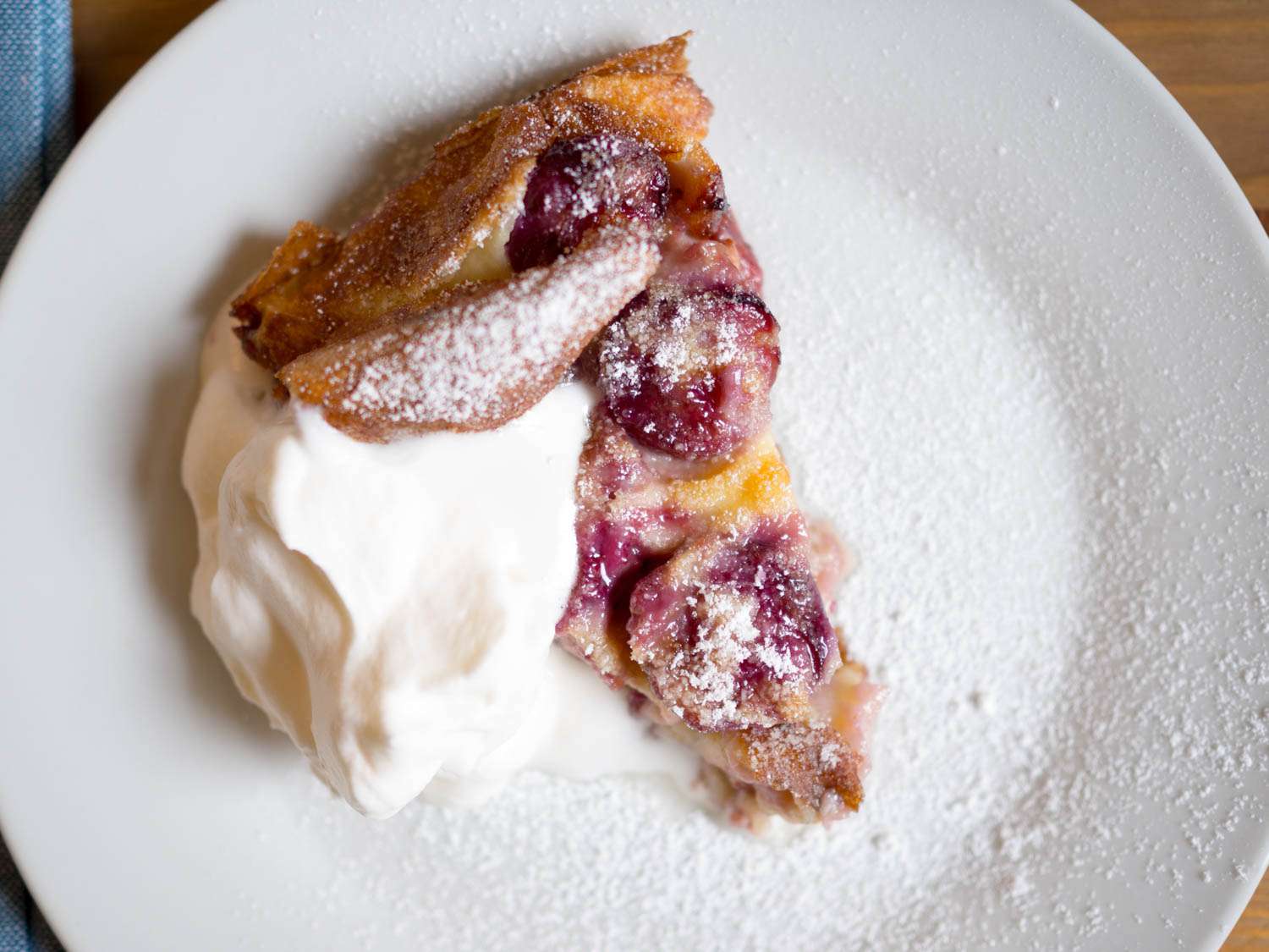 Cherry Clafoutis dusted with powdered sugar, served with dollop of whipped cream