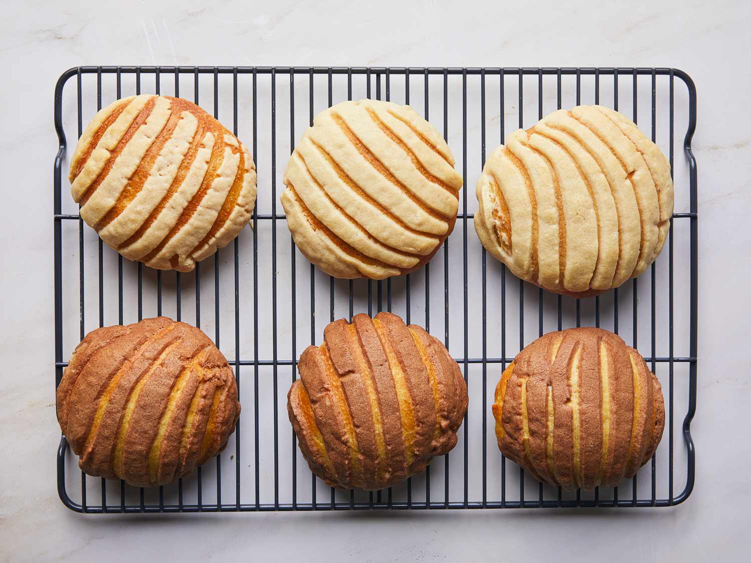 Overhead view of baked conchas resting on a wire rack