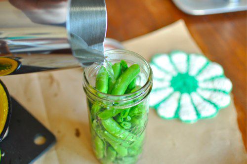 Brine poured into glass jar filled with trimmed sugar snap peas