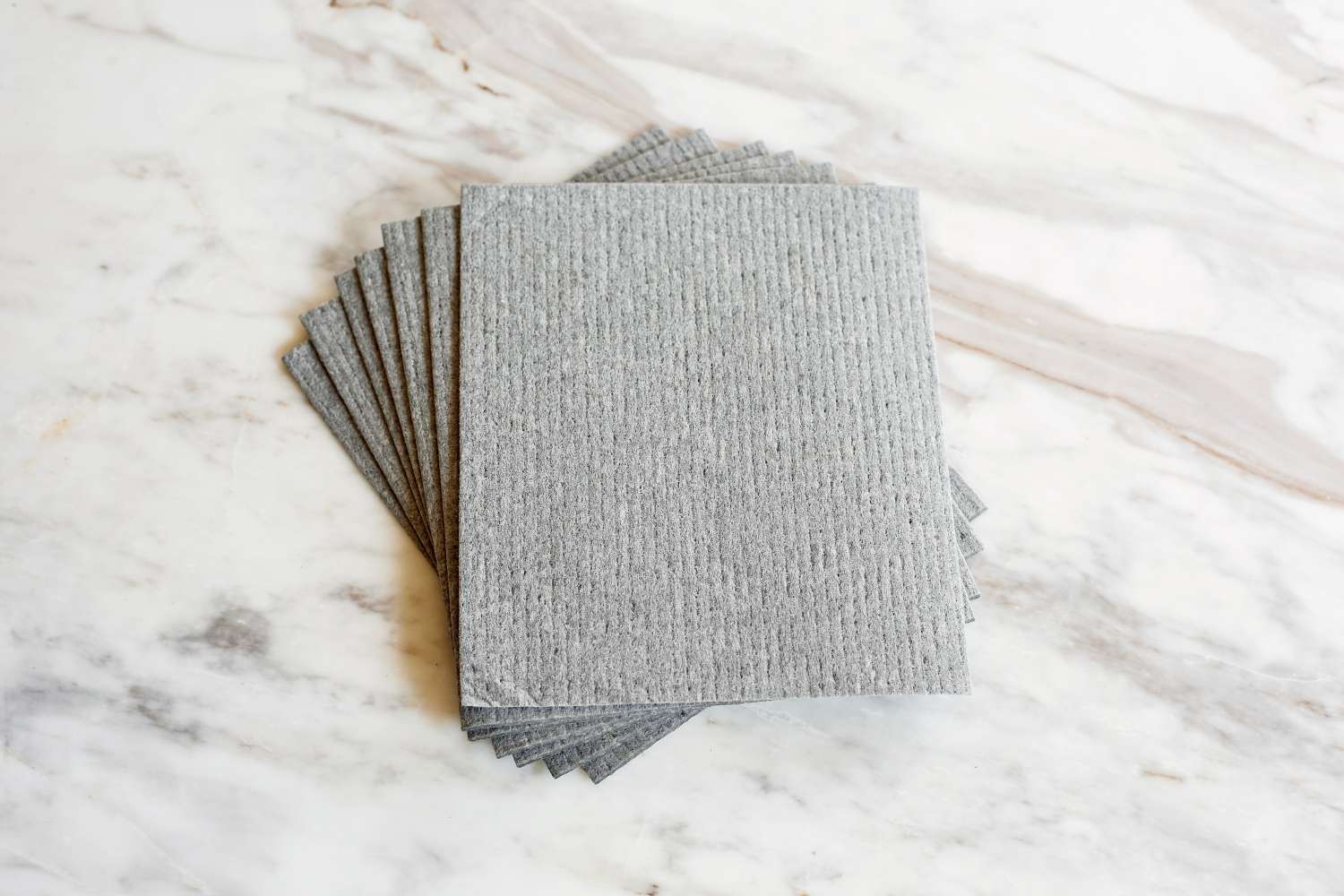 A stack of gray grey Swedish dishcloths on a marble countertop .