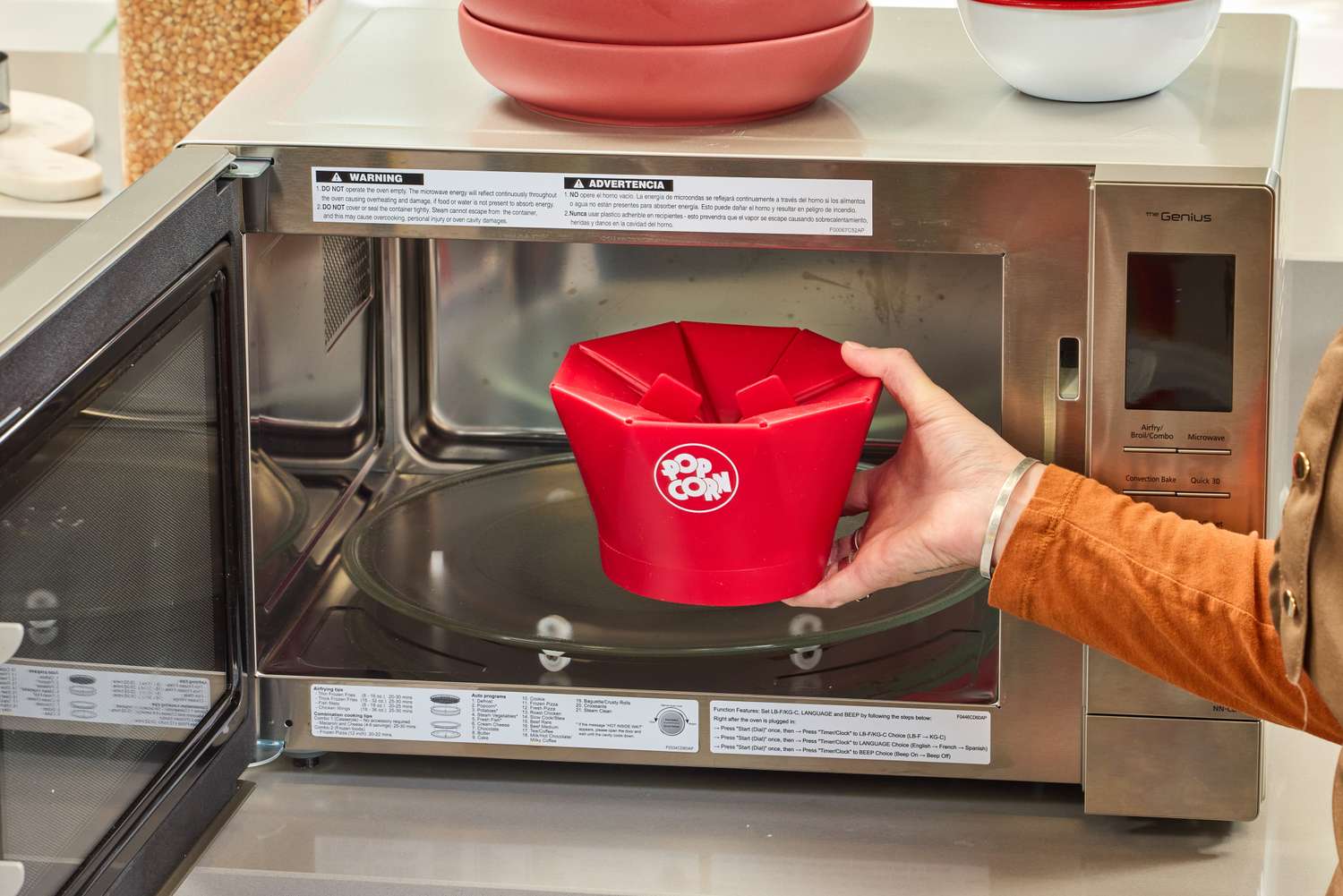 A person places the Chef'n Pop Top Microwave Popcorn Maker into a microwave