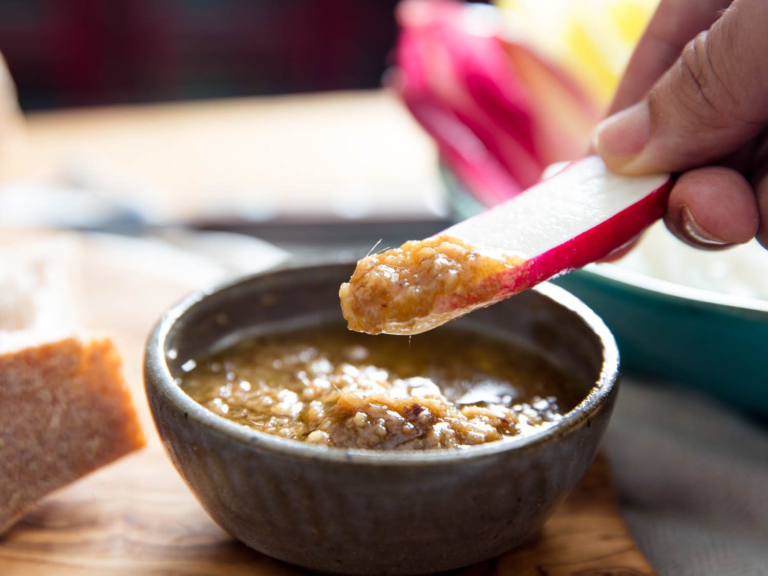 A vegetable slice being dipped into a bowl of bagna càuda