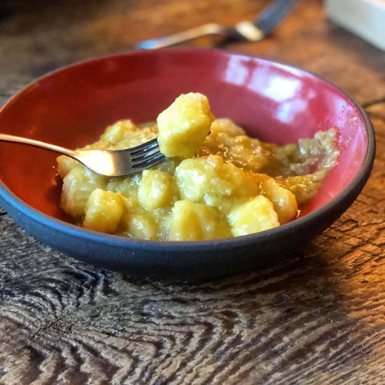 Bowl of potato gnocchi in a sauce of sauce is garlic, shallots, and yellow tomato passata