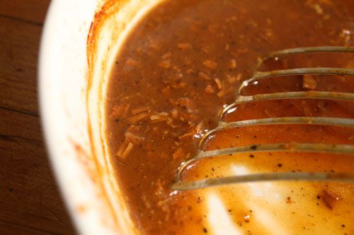 Closeup of a metal spatula stirring gravy.