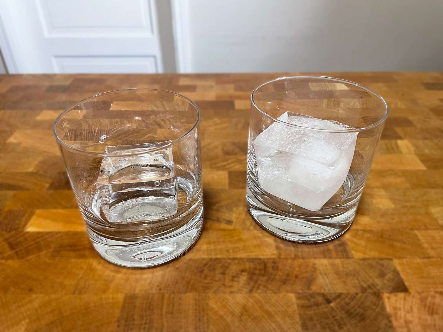 two ice cubes, one made in the true cubes ice maker and one in a normal ice mold; the one from the true cubes is clear while the other is cloudy