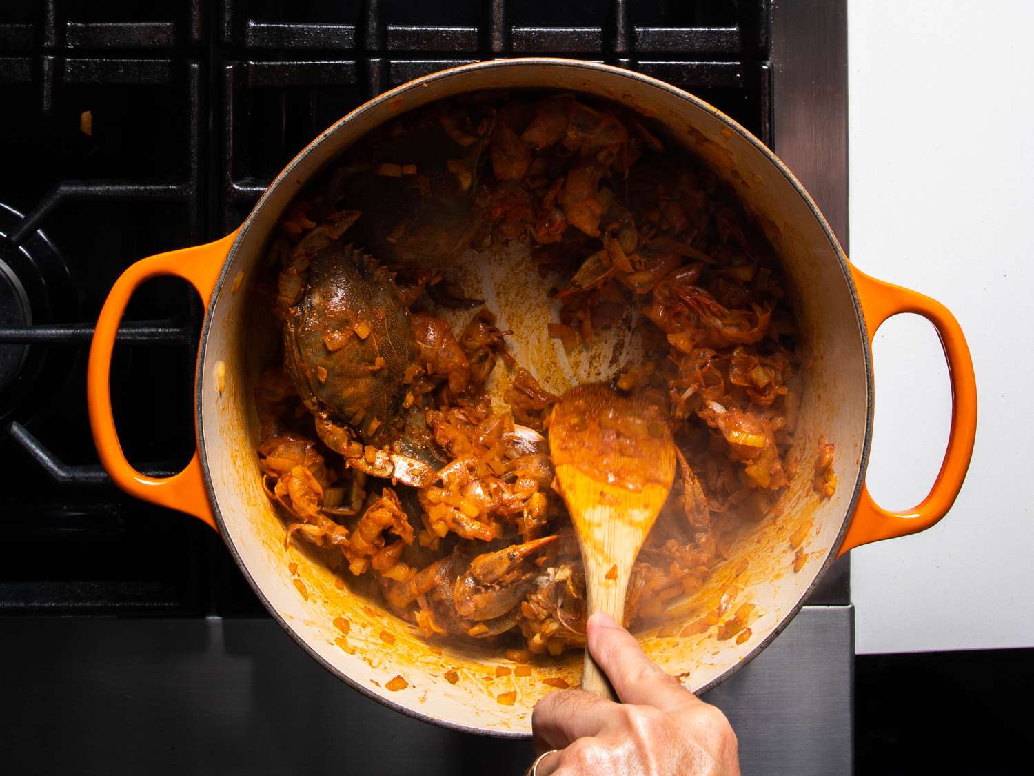 Crabs in the pot, coated in the tomato paste and aromatics.