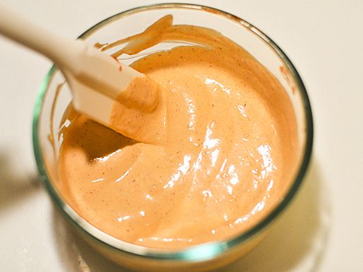 Using a small spatula to mix together sriracha, mayonnaise, and lime juice in a bowl.