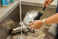 Person cleaning food tray of KitchenAid KSMMGA Metal Food Grinder Attachment