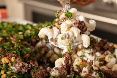 Plate of pasta with ground beef and herbs being served