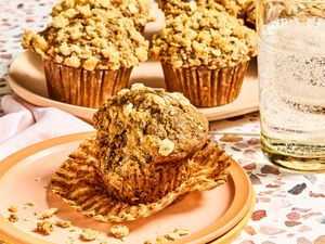 A tray and a plate of banana oatmeal muffins with a glass of sparkling water