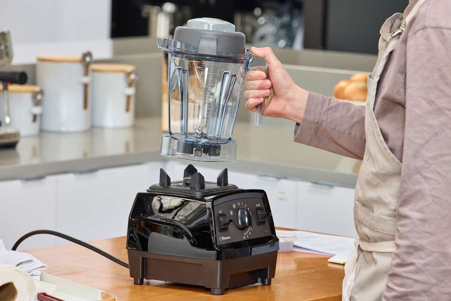 A person lifting the Vitamix Propel 510 jar over its base on a wooden surface