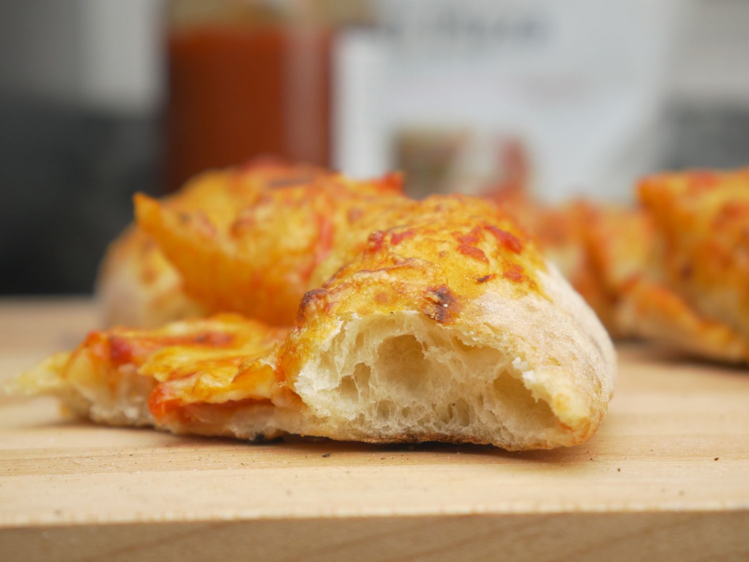 A piece of pizza with a thick crust on a wooden surface