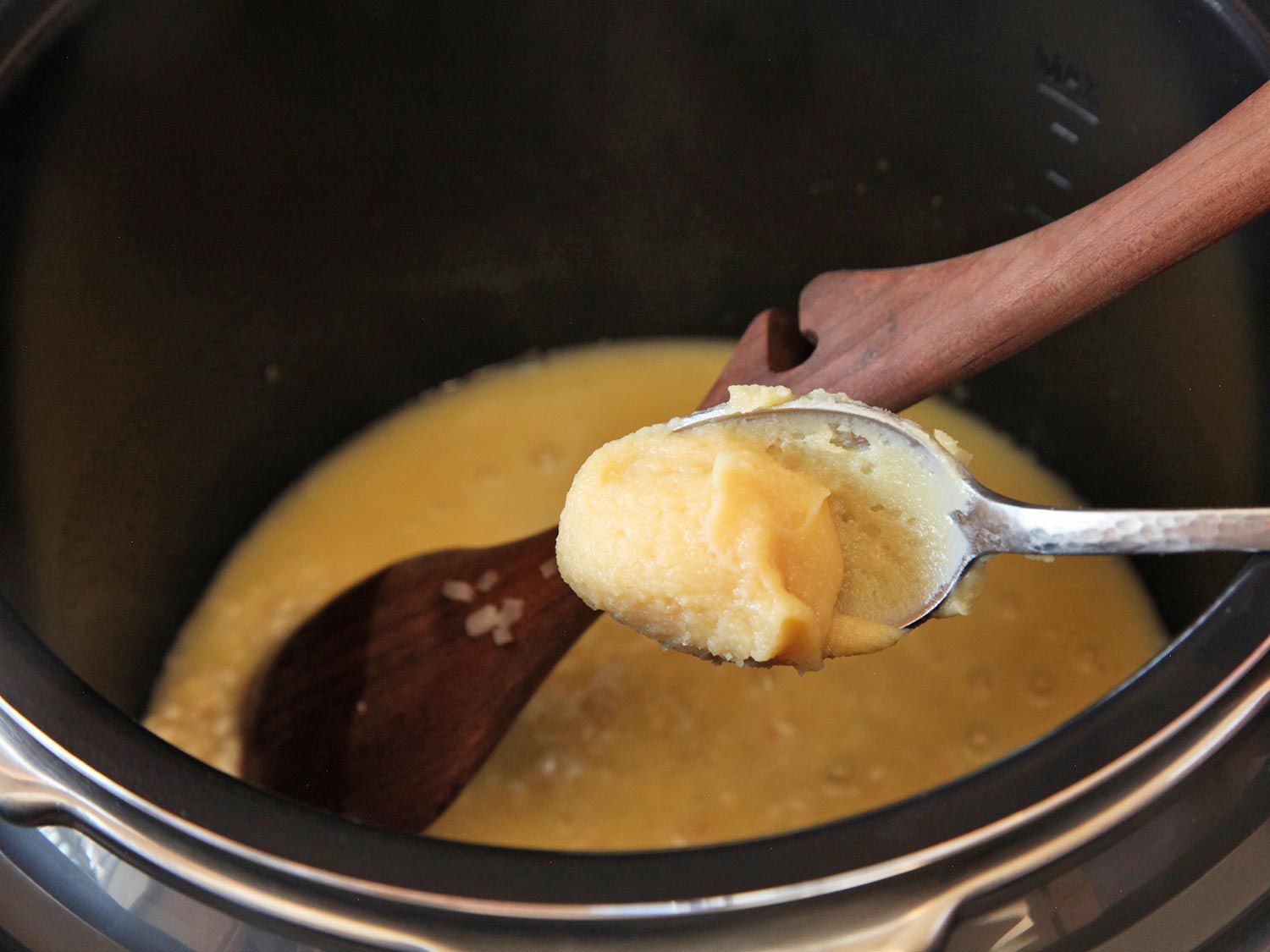 Adding a spoonful of miso paste to pressure cooker of risotto.