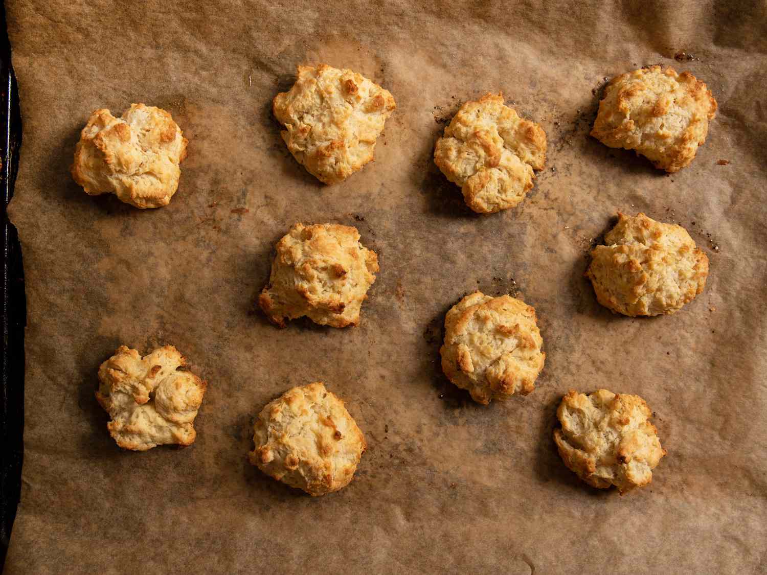 Baked drop biscuits on a parchment-lined baking sheet.