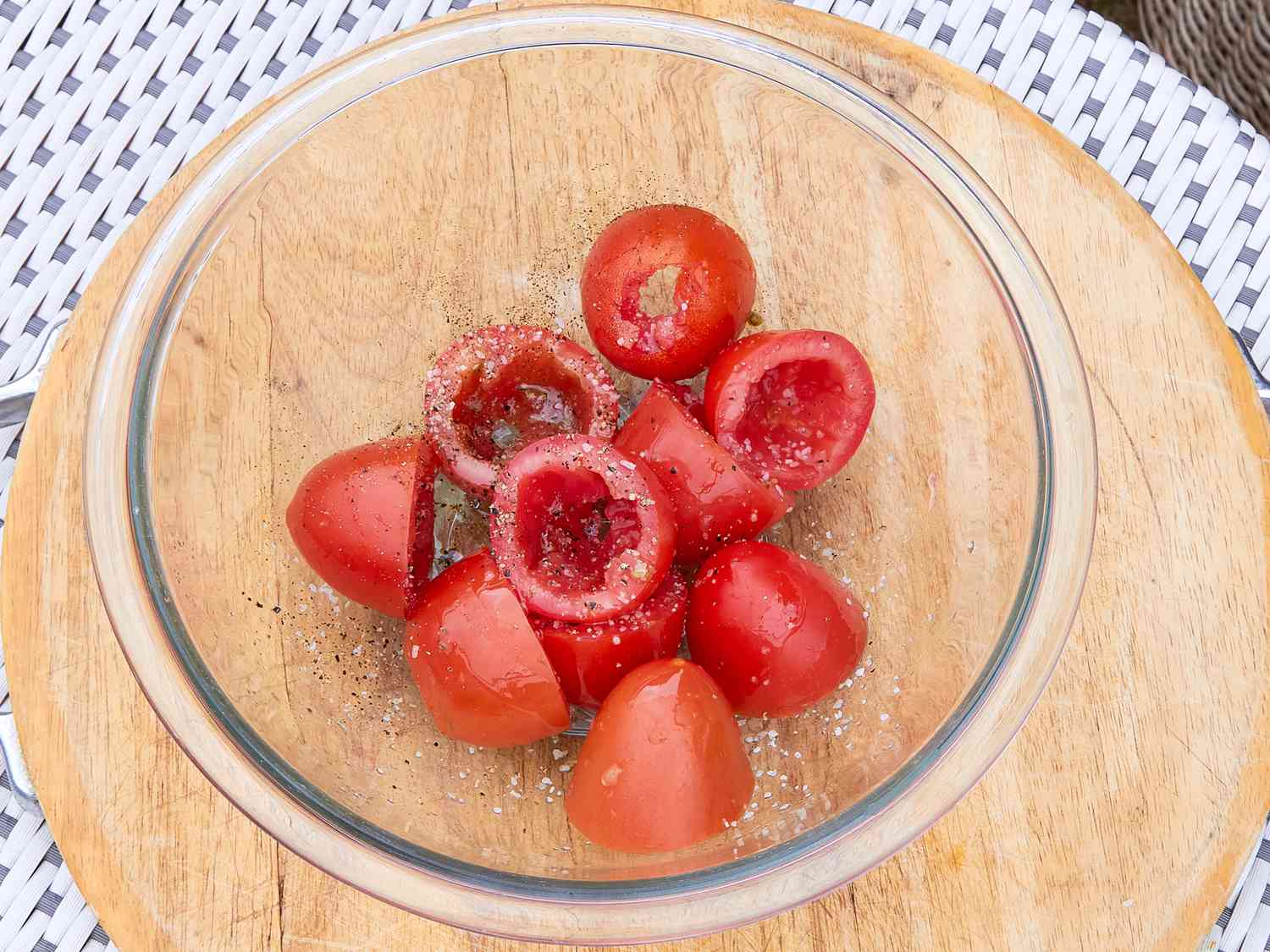 Tomato pieces in a glass bowl sprinkled with seasoning